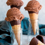 Three servings of chocolate ice cream on sugar cones.