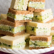 Close up photo of stack of cucumber sandwiches on a cake stand.