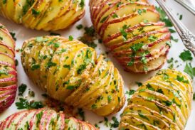Hasselback Potatoes shown sliced with parmesan and parsley on top.