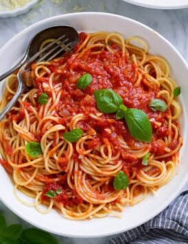 Marinara sauce tossed with spaghetti in a pasta bowl.