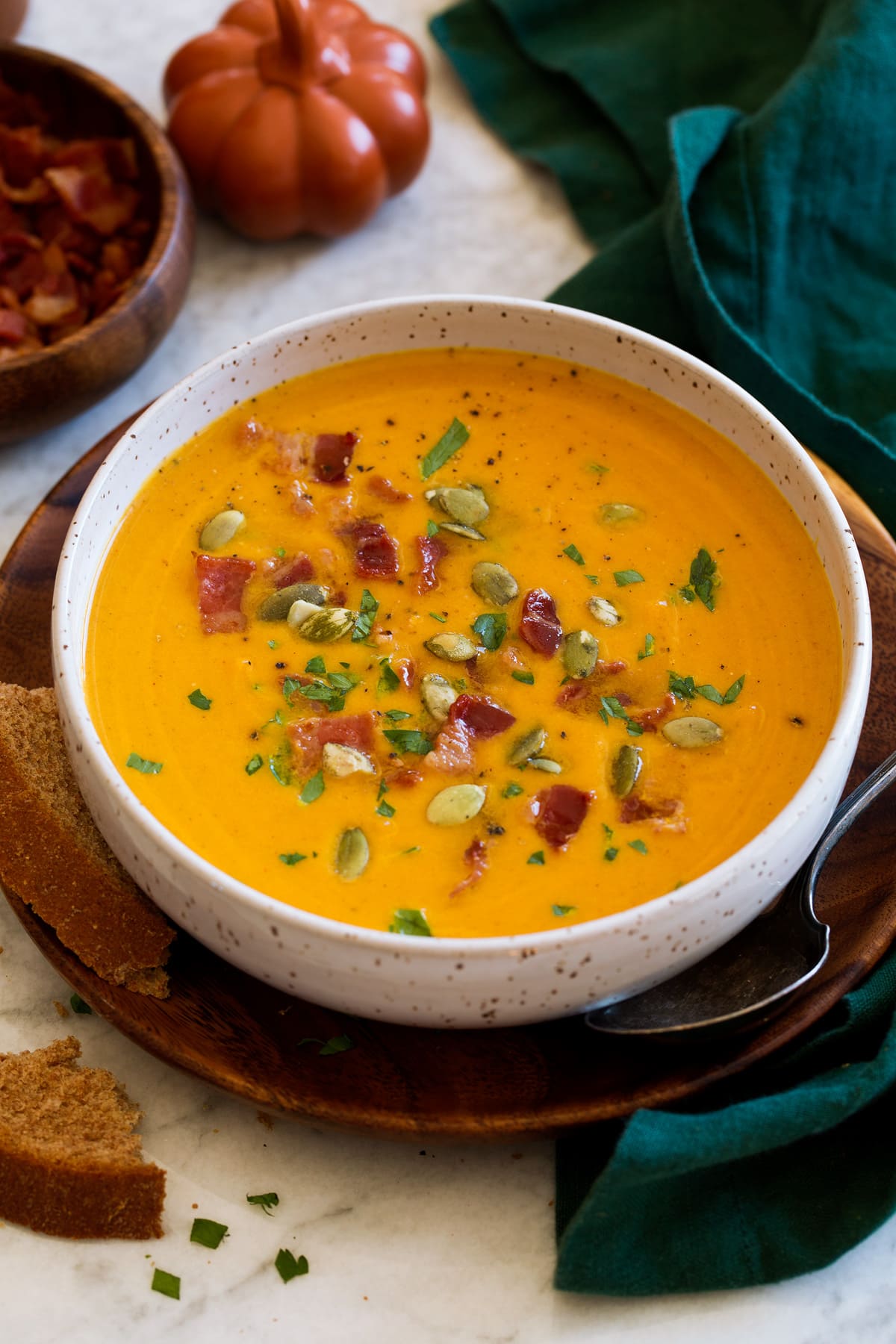 Single serving of pumpkin soup topped with bacon, parsley and pumpkin seeds.